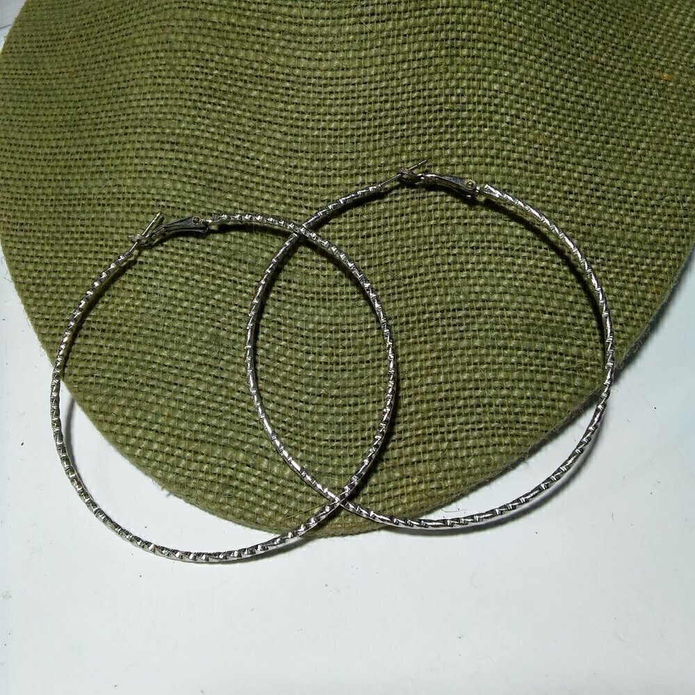 Women`s silver tone textured hoop earrings. 2 3/4